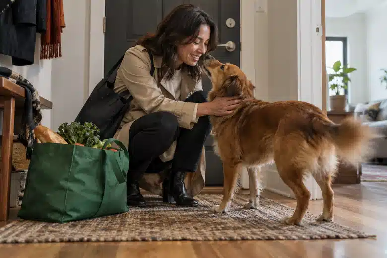 Woman greeting a brown dog in a modest apartment hallway