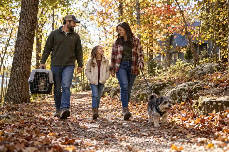 Family walking a dog on an autumn woodland path with a cat carrier